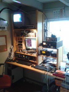 An average view of my ham radio shack: radio's, wires going arround, and the desk cluttered with homebrew and experiments.
